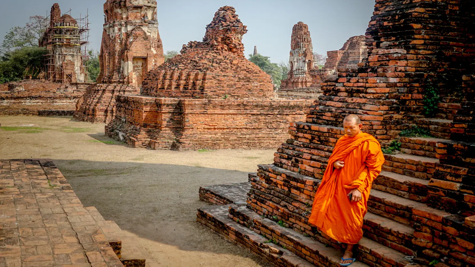 Moine en robe safran gravissant les marches d'un temple en Asie du Sud-Est