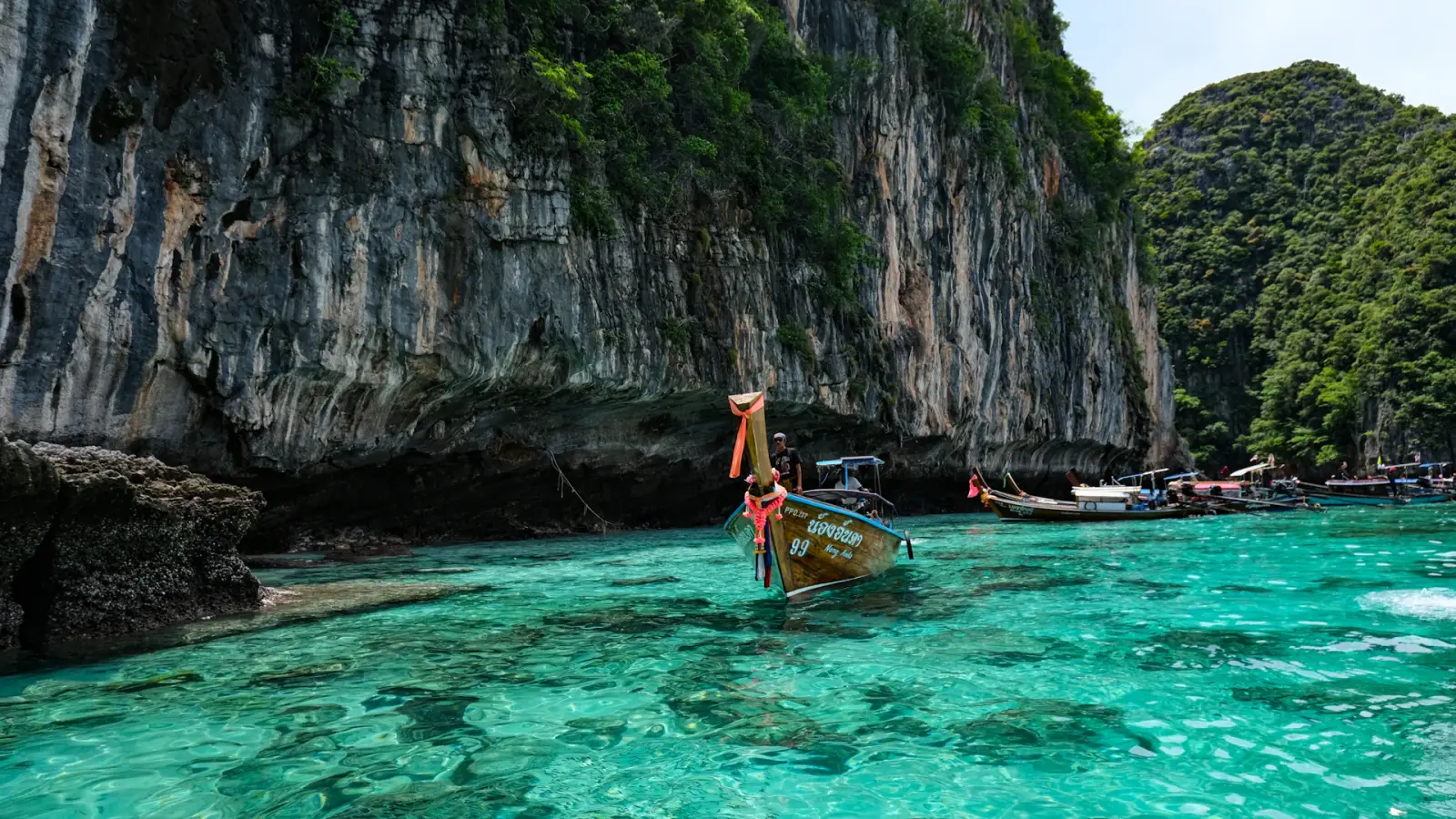 Bateaux à longue queue sur une eau turquoise au pied de falaises en Thaïlande