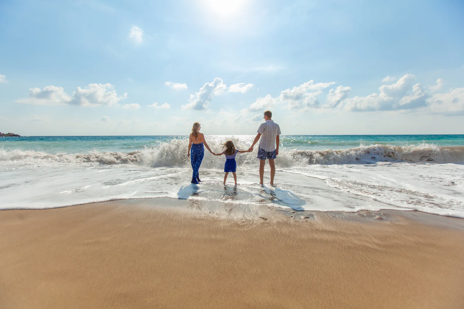 Famille se tenant la main au bord de la mer au coucher du soleil
