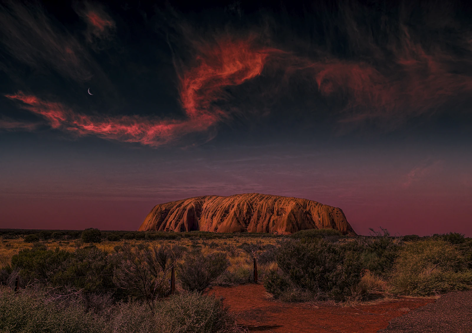 Uluru rougeoyant au coucher du soleil sous un ciel strié de nuages